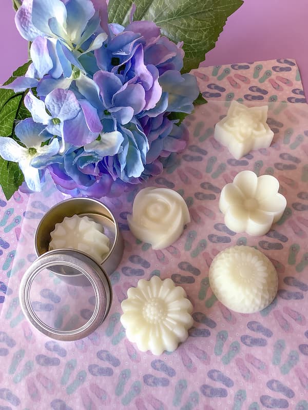 six flower lotion bars laid out, one is in a metal tin