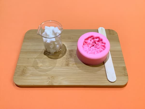 a carnation silicone mould and a beaker filled with melt and pour soap base
