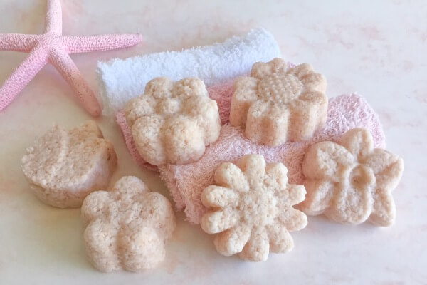 six pink bath salt cakes laying on coloured face washers