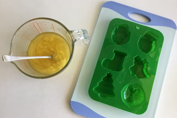 liquid lotion bar mixture sitting next to green christmas silicone mould