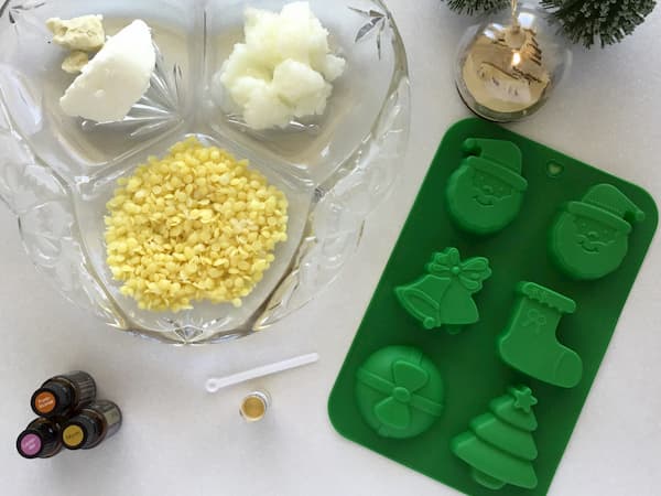 bees wax pellets, shea butter, coconut oil and gold mica laid out with a christmas themed silicone mould