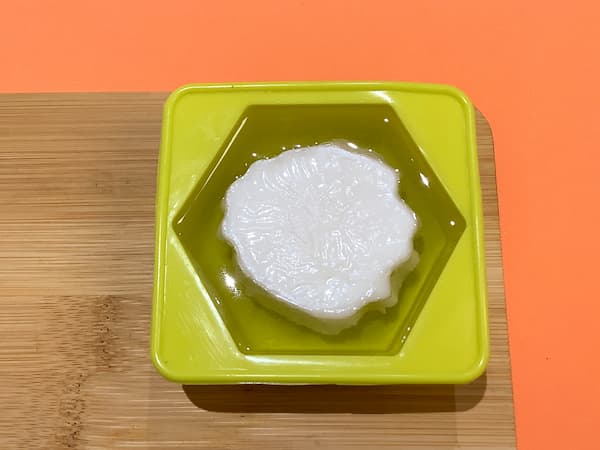 a hexagonal soap mould filled with clear melt and pour soap base with a white carnation soap bar placed upside down in the centre