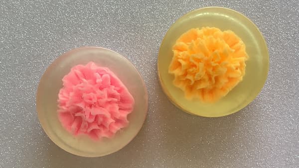 two embedded carnation soap bars sitting side by side, one pink, one orange